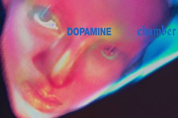 Capa do álbum Dopamine Chamber, do Fontaines D.C., com rosto em close iluminado por tons de rosa e azul e o título do disco.