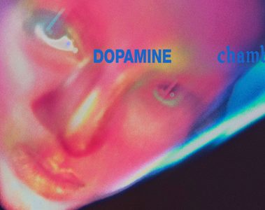 Capa do álbum Dopamine Chamber, do Fontaines D.C., com rosto em close iluminado por tons de rosa e azul e o título do disco.
