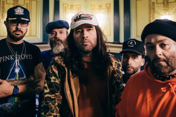 Os cinco integrantes do Alexisonfire posam juntos em fotografia promocional, usando bonés, gorros e roupas casuais, em um ambiente interno.