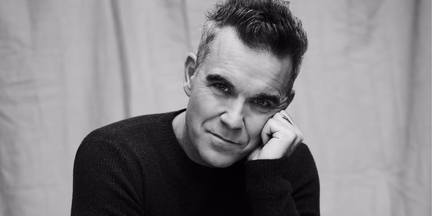 Retrato em preto e branco de Robbie Williams, que retorna ao Brasil para show em São Paulo