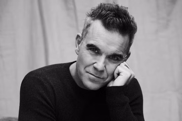 Retrato em preto e branco de Robbie Williams, que retorna ao Brasil para show em São Paulo